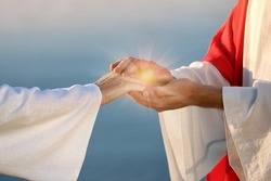 Jesus Christ and woman near water outdoors, closeup. Miraculous light in hands