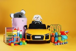 Child's electric car with other toys on yellow background