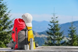Backpack and other camping gear on wooden surface outdoors, space for text. Mountain tourism