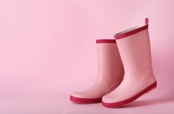 Pair of rubber boots on pink background, space for text