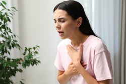 Young woman suffering from breathing problem indoors