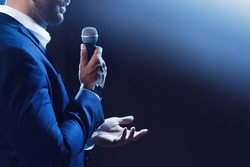 Motivational speaker with microphone performing on stage, closeup. Space for text