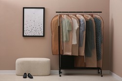 Garment bags with clothes hanging on rack in room