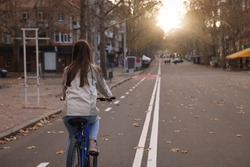 Woman riding bicycle on lane in city, back view