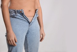 Woman in unfit jeans on light background, closeup. Space for text