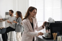 Woman preparing fresh aromatic coffee with modern machine in office