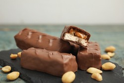 Slate board of chocolate bars with caramel, nuts and nougat on table, closeup