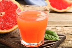 Glass of delicious grapefruit juice on wooden table, closeup