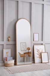 Light room interior with large mirror, beautiful pictures and pouf near wall