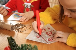 Cute little child making beautiful Christmas greeting card at wooden table, closeup