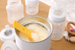 Can of powdered infant formula with scoop on table, closeup. Baby milk