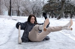 Young woman fallen on slippery icy pavement in park