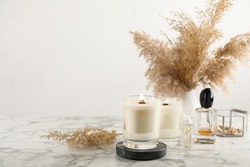 Composition with burning soy candles on white marble table, space for text