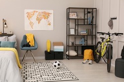 Stylish teenager's room interior with comfortable bed and sports equipment