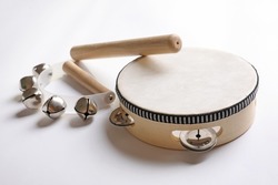 Wooden tambourine, rhythm stick and hand bells on white background. Montessori musical toy