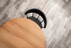 Round wooden table and black chair indoors, top view
