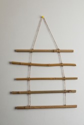 Beautiful decor element made of dry bamboo sticks hanging on white wall