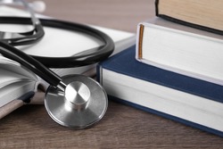 Student textbooks and stethoscope on wooden table, closeup. Medical education