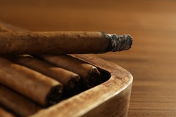 Many cigars in box on wooden table, closeup