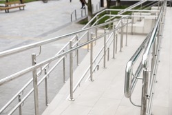 Tiled ramp with shiny metal railings outdoors