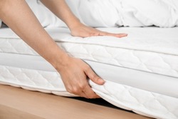 Woman touching soft white mattress on bed, closeup