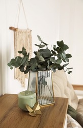 Stylish glass vase with eucalyptus branches and beautiful decor elements on wooden table indoors