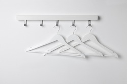 Rack with empty clothes hangers on white wall