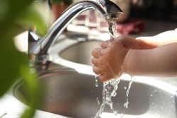 Little child washing hands in kitchen, closeup view