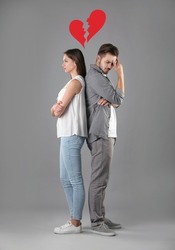 Upset young couple and illustration of broken heart on grey background. Relationship problems
