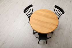 Stylish round table with black chairs on floor, above view