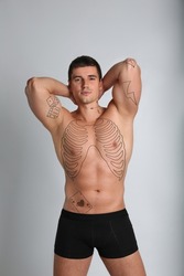 Handsome man with beautiful tattoo sketches on light background