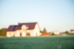 Blurred view of beautiful house with green lawn on sunny day