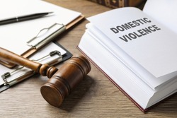 Wooden gavel and law book on wooden table. Protection from domestic violence