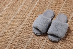 Soft fluffy grey slippers on carpet, space for text
