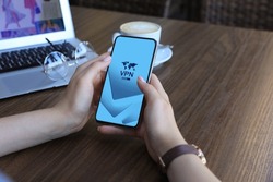 Woman using smartphone with switched on VPN at wooden table, closeup