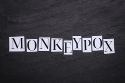 Word Monkeypox made of paper letters on black background, top view