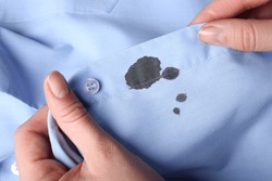 Woman holding shirt with black ink stain, closeup