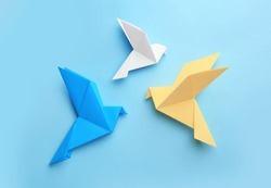 Origami art. Colorful handmade paper birds on light blue background, flat lay