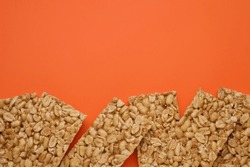 Tasty peanut bars (kozinaki) on orange background, flat lay. Space for text