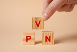 Woman making acronym VPN with wooden cubes on beige background, closeup