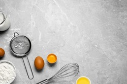 Ingredients for crepes, whisk and sieve on light grey table, flat lay. Space for text