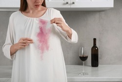 Woman with wine stain on her clothes indoors, closeup. Space for text