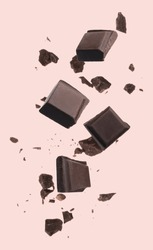 Pieces of chocolate bar falling on beige background