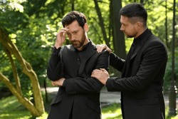 Funeral ceremony. Man comforting his friend outdoors
