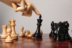 Robot moving chess piece on board against light grey background, closeup. Wooden hand representing artificial intelligence