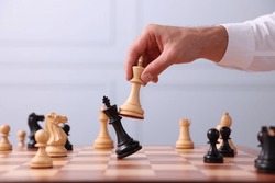 Man moving king chess piece at checkerboard indoors, closeup