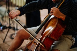 Cellist plays music on a cello with a bow. Shallow depth of field and selective sharpness