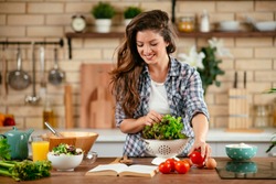 Beautiful young woman is preparing vegetable salad in the kitchen. Healthy Food. Vegan Salad. Diet. Dieting Concept. Healthy Lifestyle. Cooking At Home.