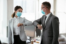 Businessman and businesswoman with medical mask in office. Greetings in Covid-19 time.