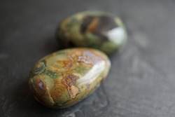 Orbicular jasper (or ocean jasper) tumbled pebbles on gray slate background
